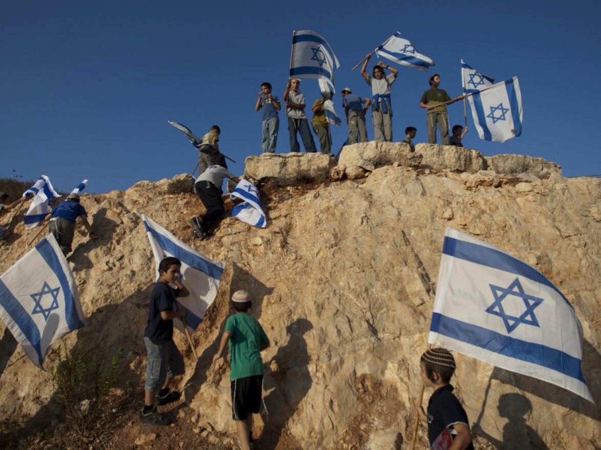 Israeli settler youths wave Israeli flags at the start of a protest march against Palestinian statehood, from the West Bank Jewish settlement of Itamar, on Tuesday.